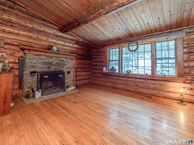 a view of an empty room with wooden floor fireplace and a window