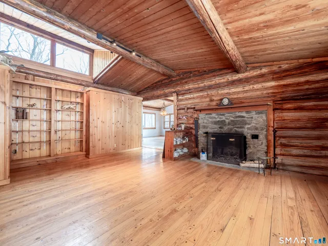 a view of an empty room with wooden floor a ceiling fan and windows