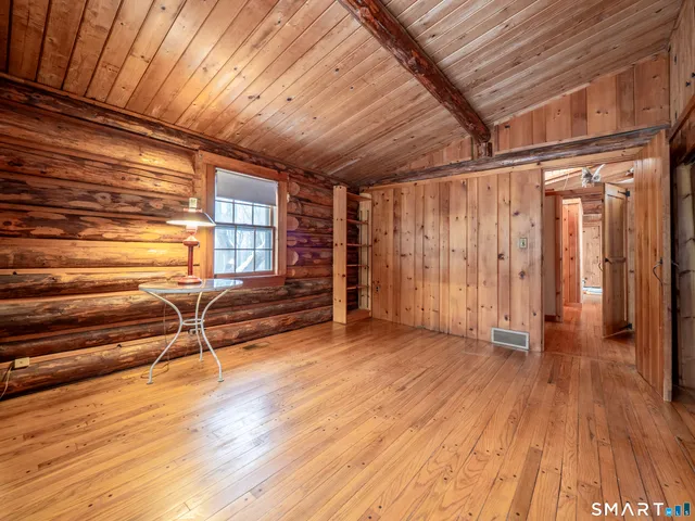 a view of an empty room with wooden floor and windows