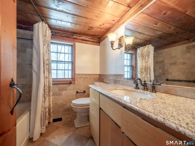 a bathroom with a granite countertop sink toilet and shower