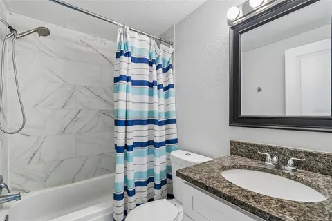 a bathroom with a granite countertop sink a mirror and shower