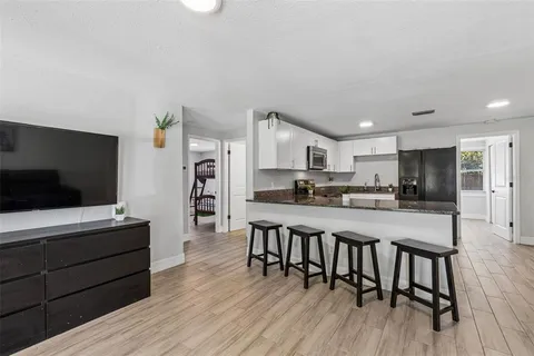 a living room with stainless steel appliances furniture and a flat screen tv