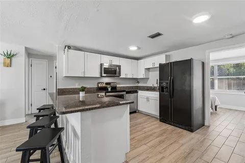 a kitchen with a refrigerator a sink dishwasher and a stove top oven with wooden floor