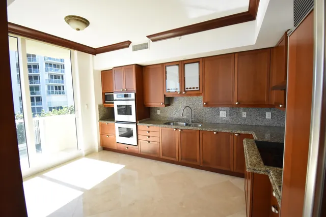 a kitchen with stainless steel appliances granite countertop a stove a sink and a refrigerator with wooden floor