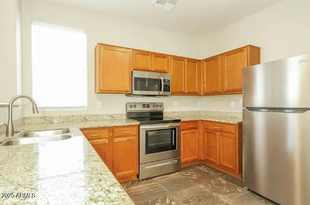 a kitchen with stainless steel appliances granite countertop a refrigerator stove top oven and sink