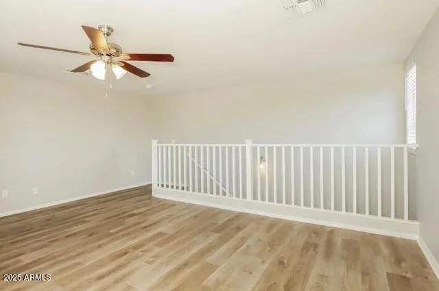an empty room with wooden floor fan and windows