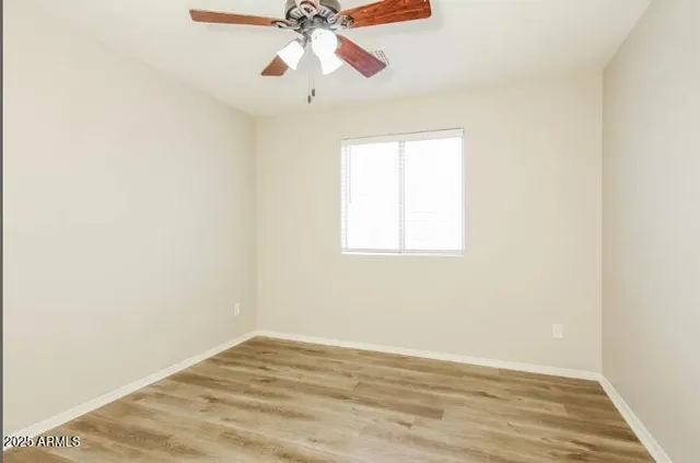 an empty room with wooden floor fan and windows