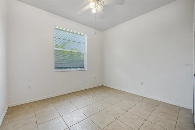an empty room with a chandelier fan and windows