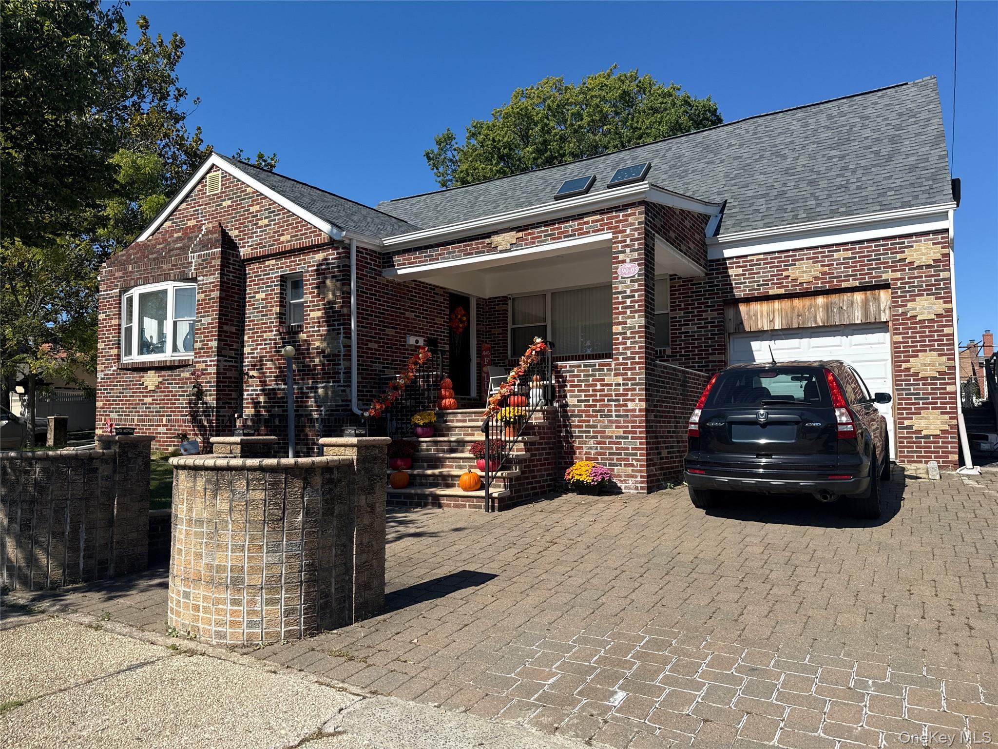 View of front of home featuring brick siding, a shingled roof, an attached garage, and a porch