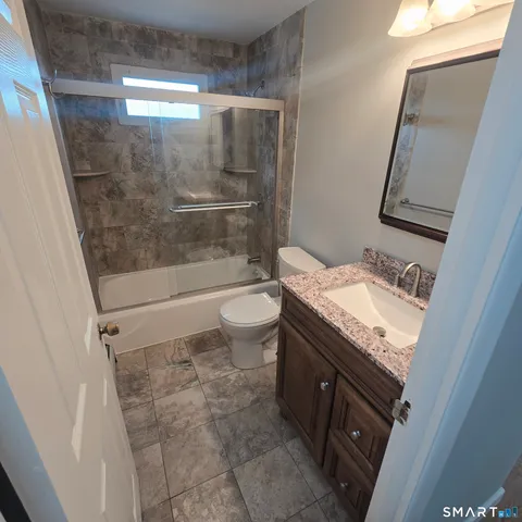 a bathroom with a granite countertop sink toilet and shower