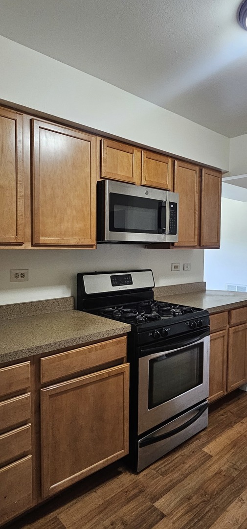 833 Village Quarter Road, Unit A3 West Dundee, IL 60118 - Photo 7 of 27 a kitchen with appliances cabinets and a wooden floor
