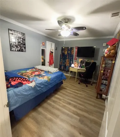 a bedroom with a bed ceiling fan and a large window