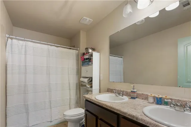 a bathroom with a granite countertop sink a toilet and a mirror