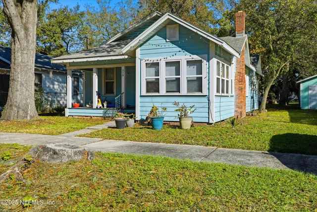 a view of a brick house next to a yard with large trees