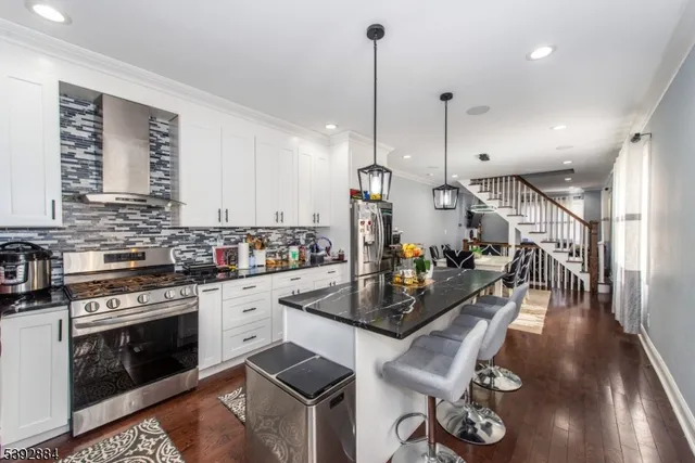 a view of a kitchen with kitchen island stainless steel appliances a stove a sink a center island and windows