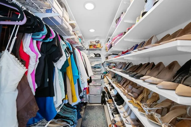 a view of walk in closet with clothes and shoes
