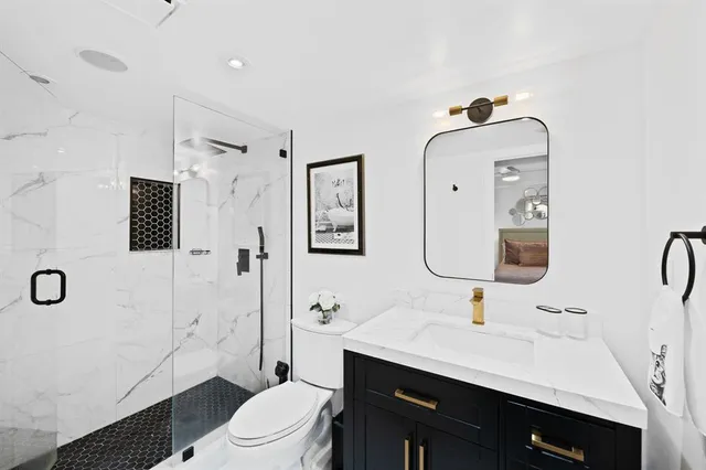 a bathroom with a double vanity sink toilet mirror and shower