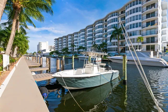 a view of a patio with couches table and chairs with potted plants and palm trees