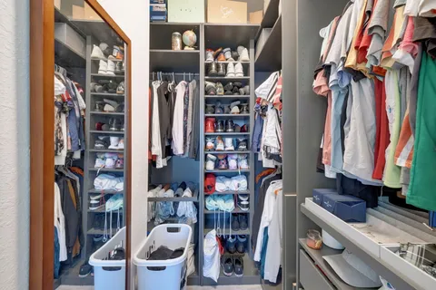a view of walk in closet with clothes and shoes