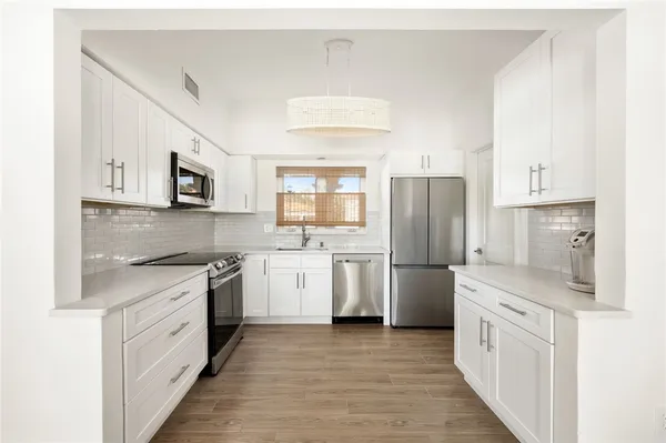 a kitchen with white cabinets and stainless steel appliances
