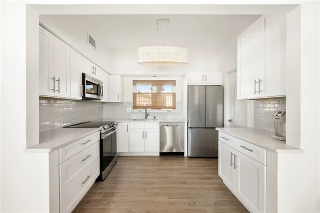 a kitchen with white cabinets and stainless steel appliances