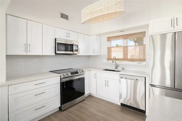 a kitchen with white cabinets white stainless steel appliances and sink