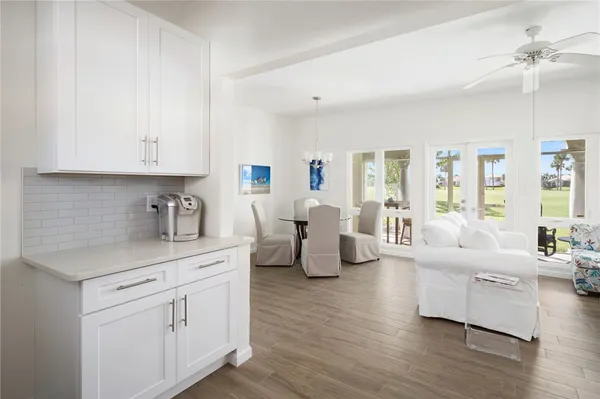 a living room with furniture white cabinets and wooden floor