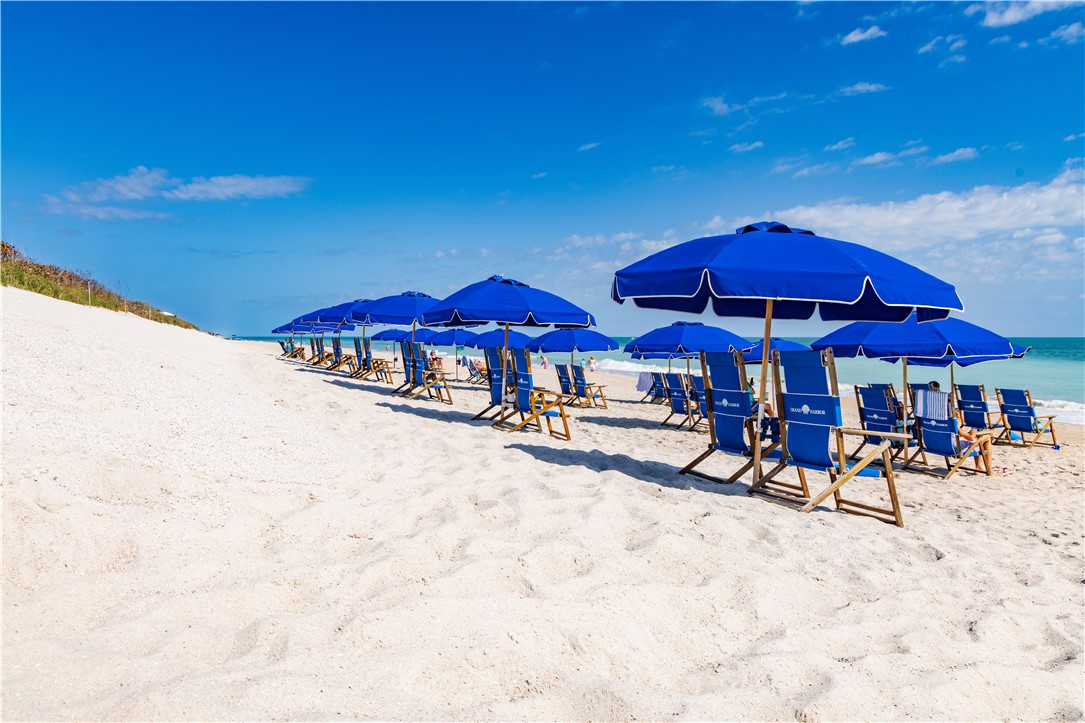 5045 Harmony Circle, Unit 102 Vero Beach, FL 32967 - Photo 24 of 28 a view of chairs and tables with umbrellas in patio