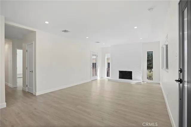an empty room with wooden floor and fireplace