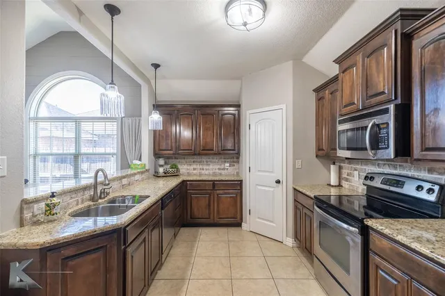 a kitchen with stainless steel appliances granite countertop a sink stove and cabinets