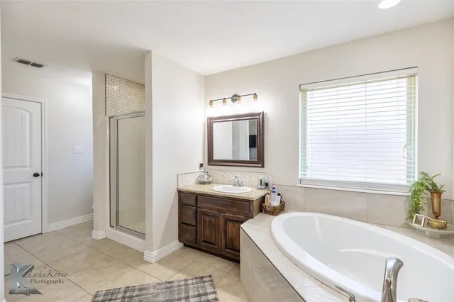 a spacious bathroom with a double vanity sink a mirror and a bathtub