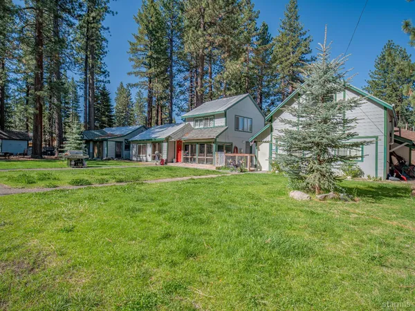 a view of a house with a big yard and large trees