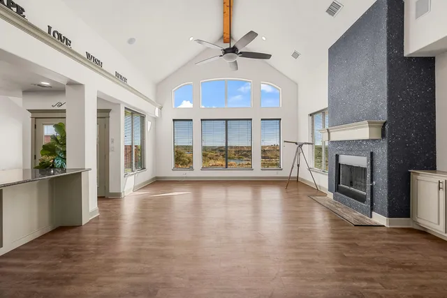 a view of an empty room with wooden floor and a fireplace