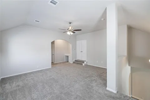 an empty room with a chandelier fan and a ceiling fan