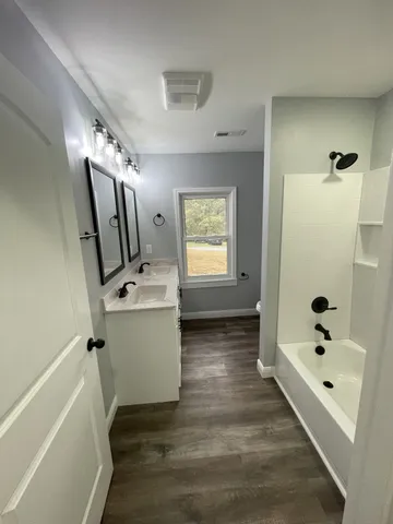 a bathroom with a tub sink and mirror