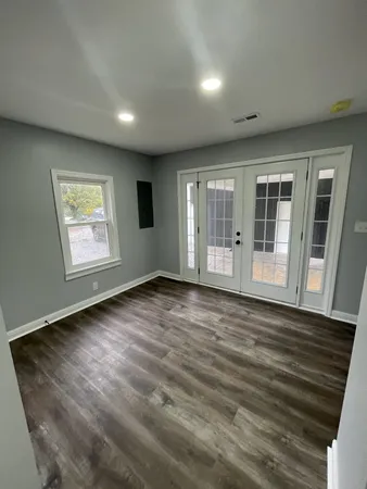 a view of an empty room with wooden floor and a window