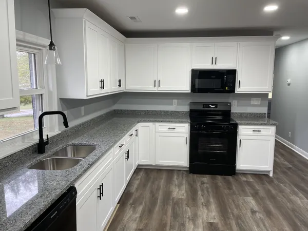 a kitchen with granite countertop a sink and white cabinets
