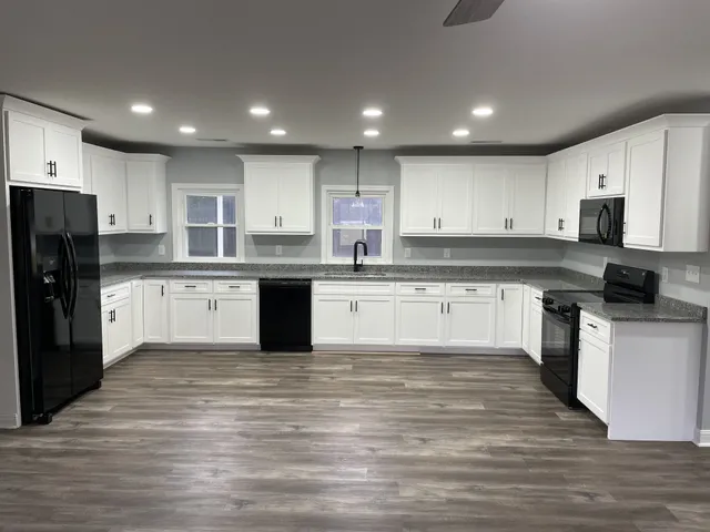 a large kitchen with cabinets a sink and wooden floor