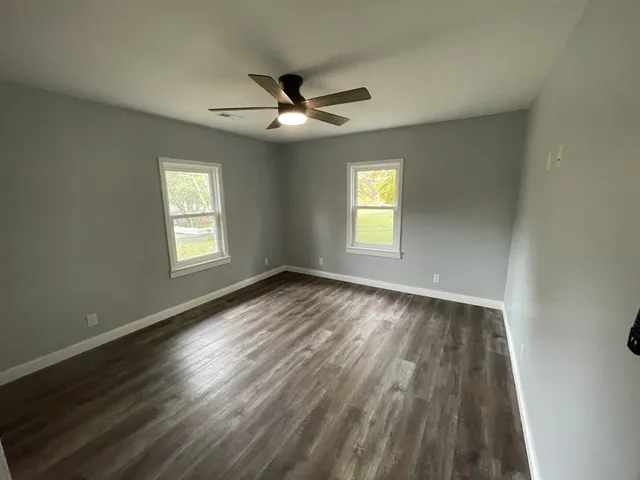 a view of empty room with wooden floor and fan