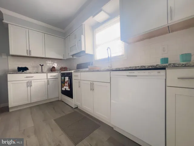 a kitchen with white cabinets sink and white appliances