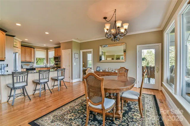 a dining room with wooden floor a chandelier a glass table and chairs