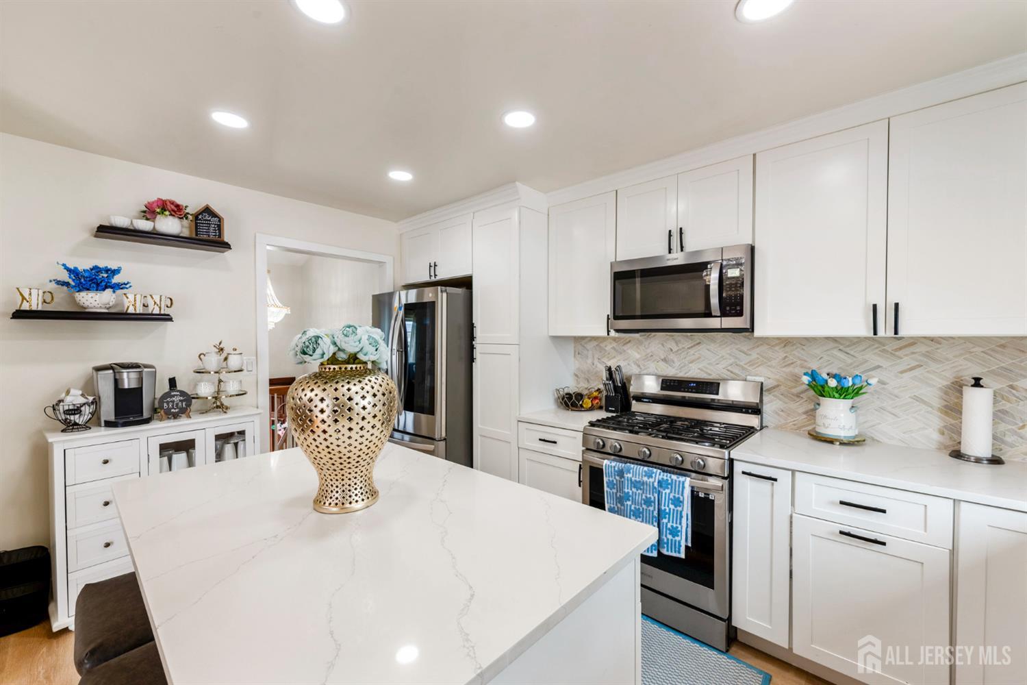 115 Vernon Way Port Reading, NJ 07064 - Photo 11 of 33 a kitchen with stainless steel appliances granite countertop a sink a stove a microwave a refrigerator a refrigerator and cabinets