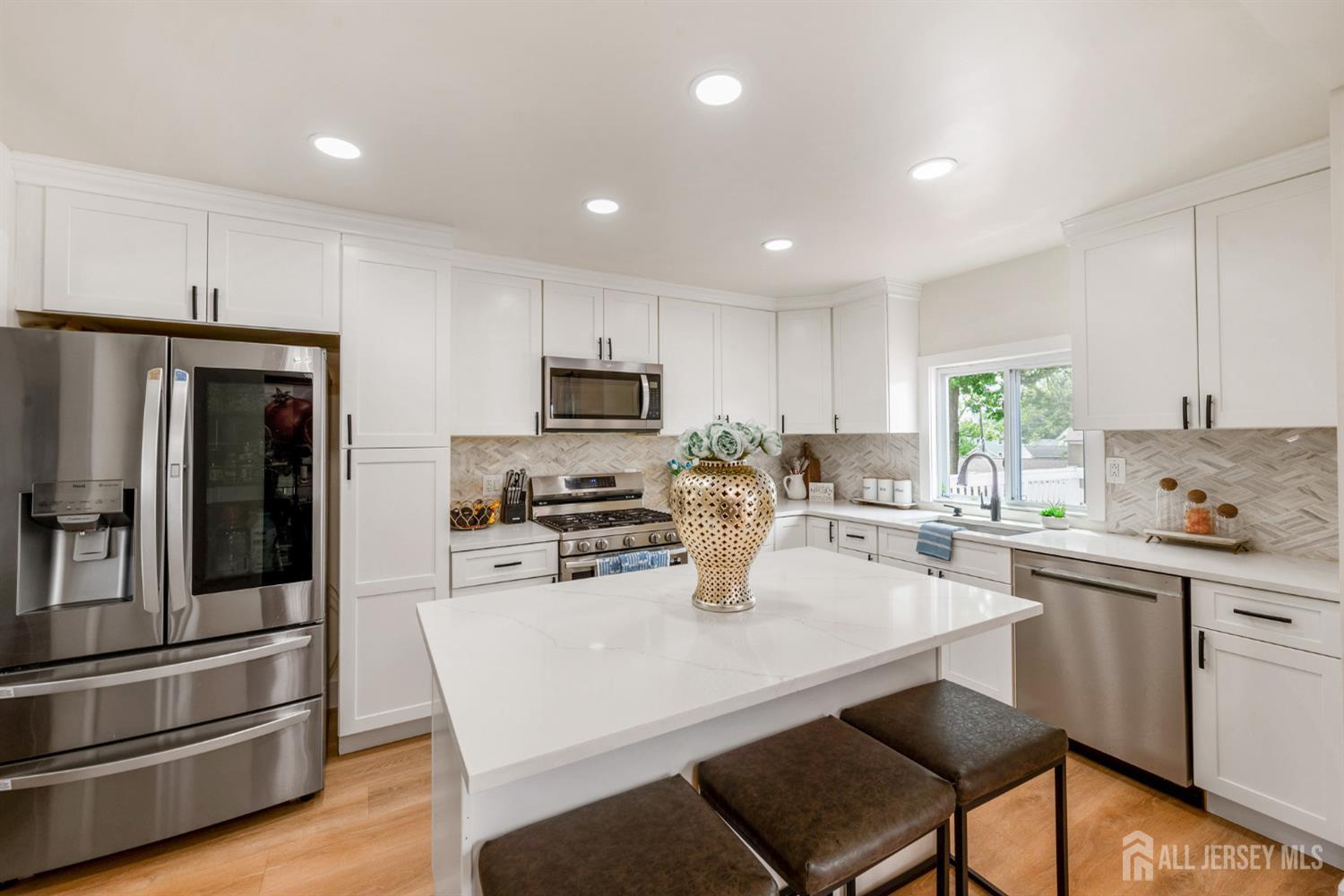 115 Vernon Way Port Reading, NJ 07064 - Photo 10 of 33 a kitchen with stainless steel appliances granite countertop a stove a refrigerator a sink a dining table and chairs