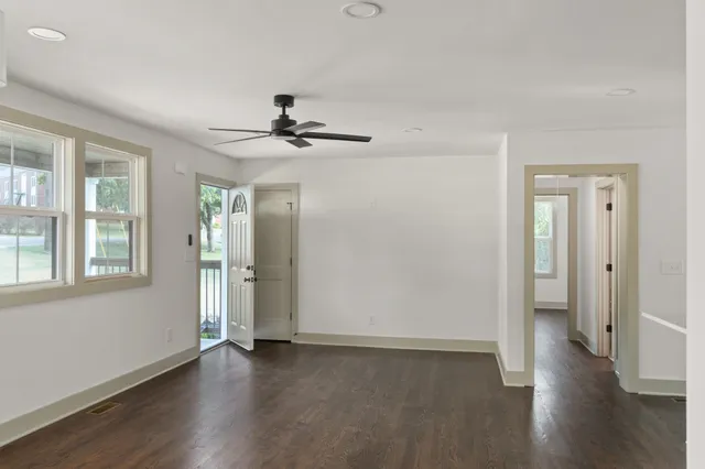 a view of an empty room with wooden floor and a window