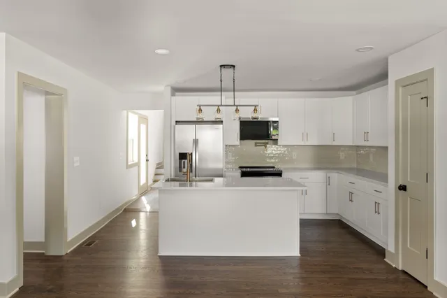 a kitchen with kitchen island white cabinets appliances and sink