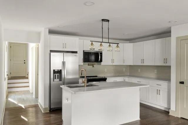 a kitchen with granite countertop a refrigerator a stove a microwave and island