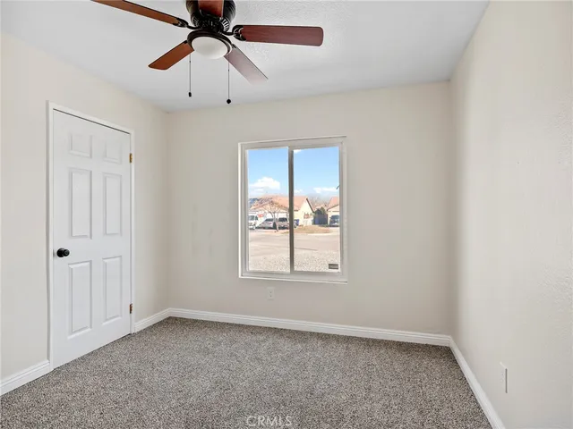 an empty room with chandelier fan and windows