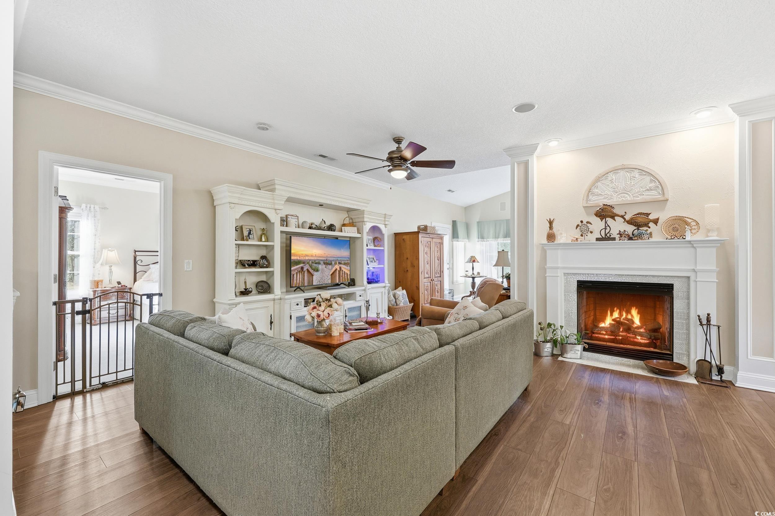 452 Deer Watch Circle Longs, SC 29568 - Photo 16 of 39 Living room featuring a lit fireplace, a ceiling fan, dark wood-style floors, and crown molding
