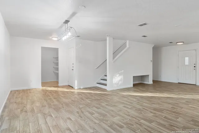 an empty room with wooden floor and ceiling fan