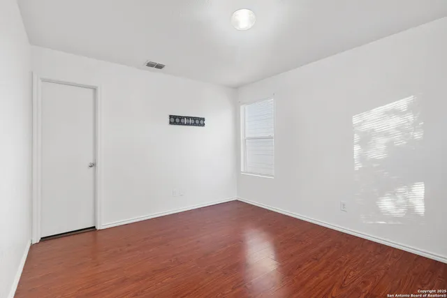 a view of an empty room with wooden floor and a window
